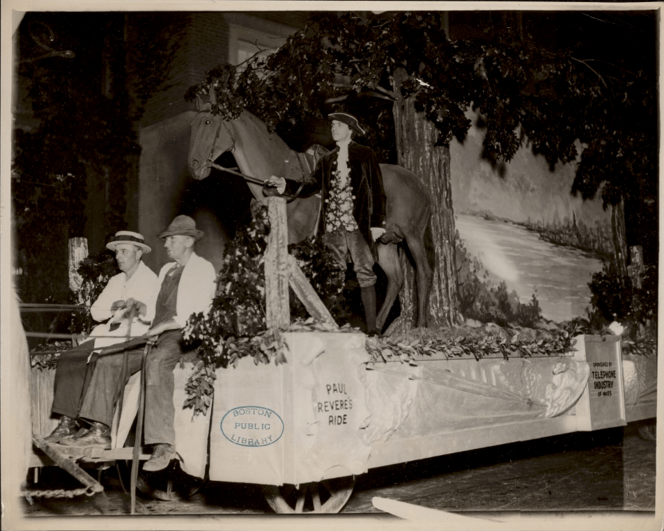 Float sponsored by the Telephone Industry in a parade celebrating Boston’s Tercentary in 1930. The centerpiece is a man dressed as Paul Revere, holding the reins of a fake horse under a fake tree.